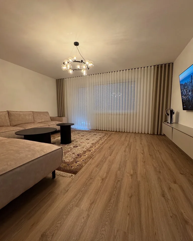 Weiße Gardinen mit taupefarbenen Seitenschals im Wohnzimmer mit beigem Ecksofa