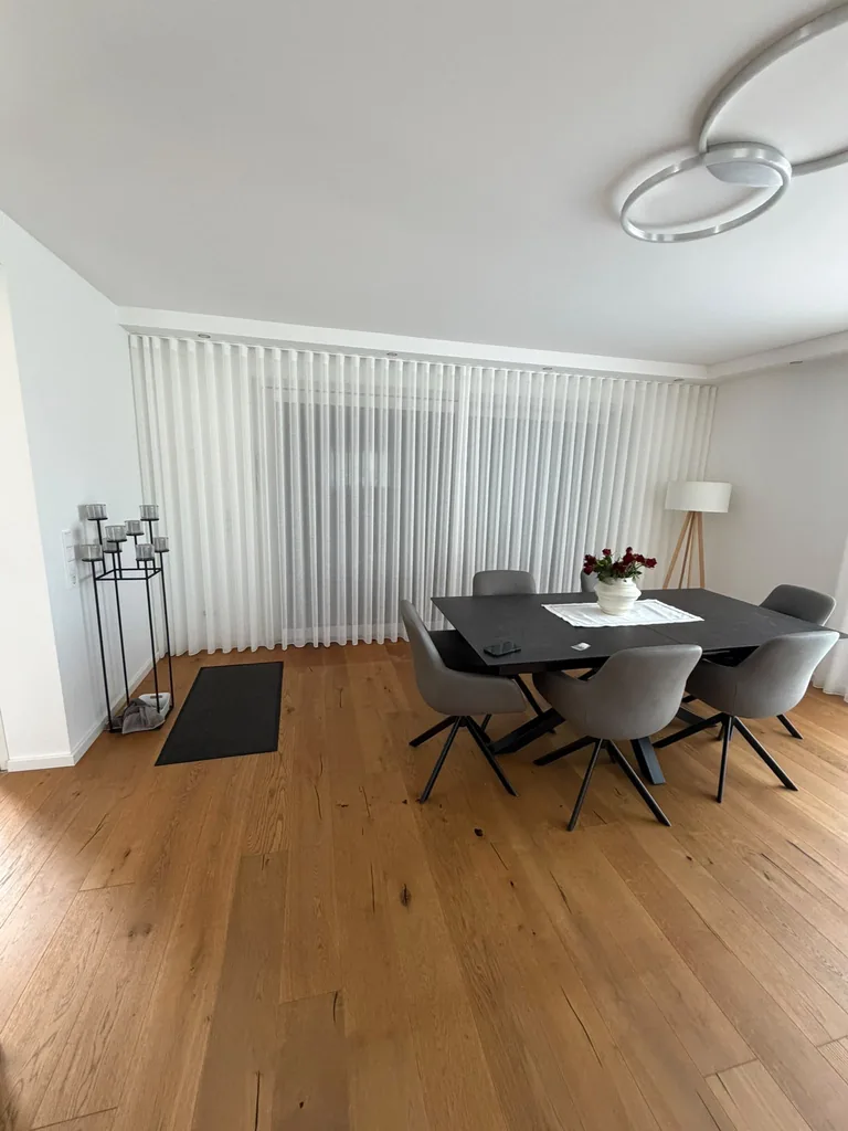 Bodenlange weiße Wellengardinen im Esszimmer mit dunklem Tisch und grauen Stühlen