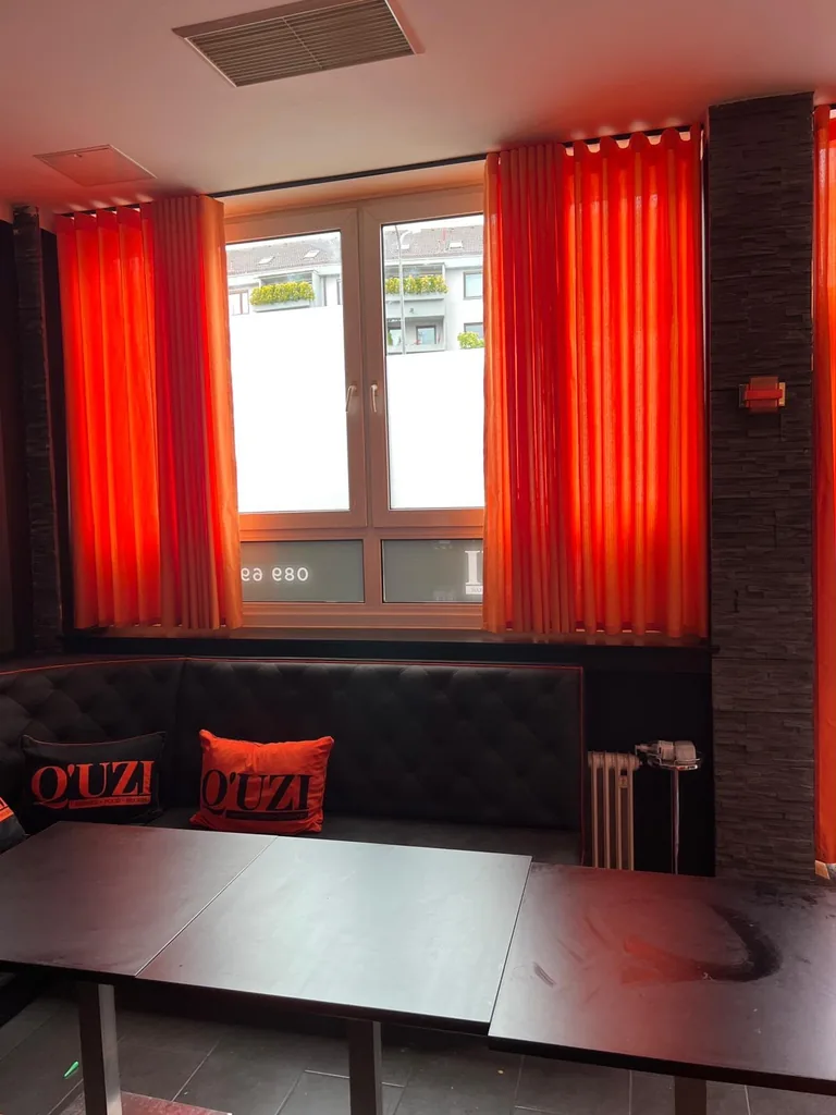 Orangefarbene Wellenvorhänge seitlich geöffnet vor einem Fenster in einer Lounge