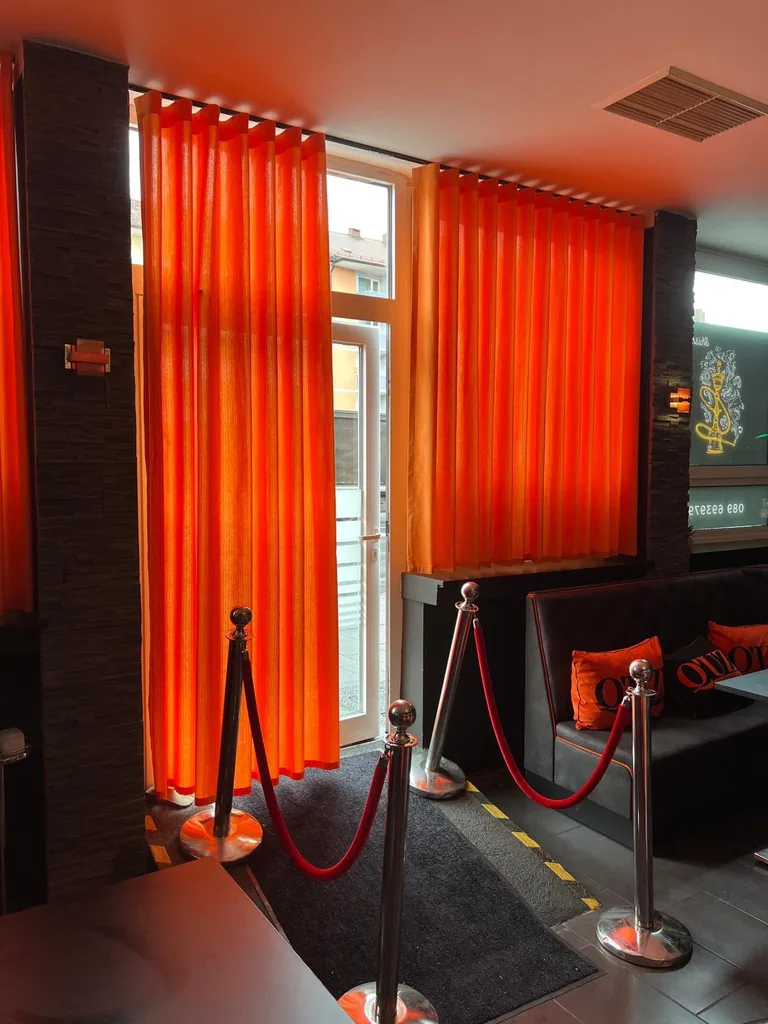Orangefarbene Gardinen an Eingangstür und Fenster einer Lounge