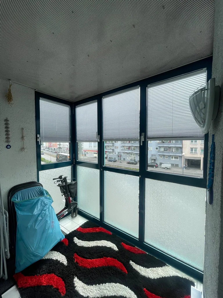 Weiße Plissees am verglasten Balkon von unten geöffnet mit freiem Ausblick