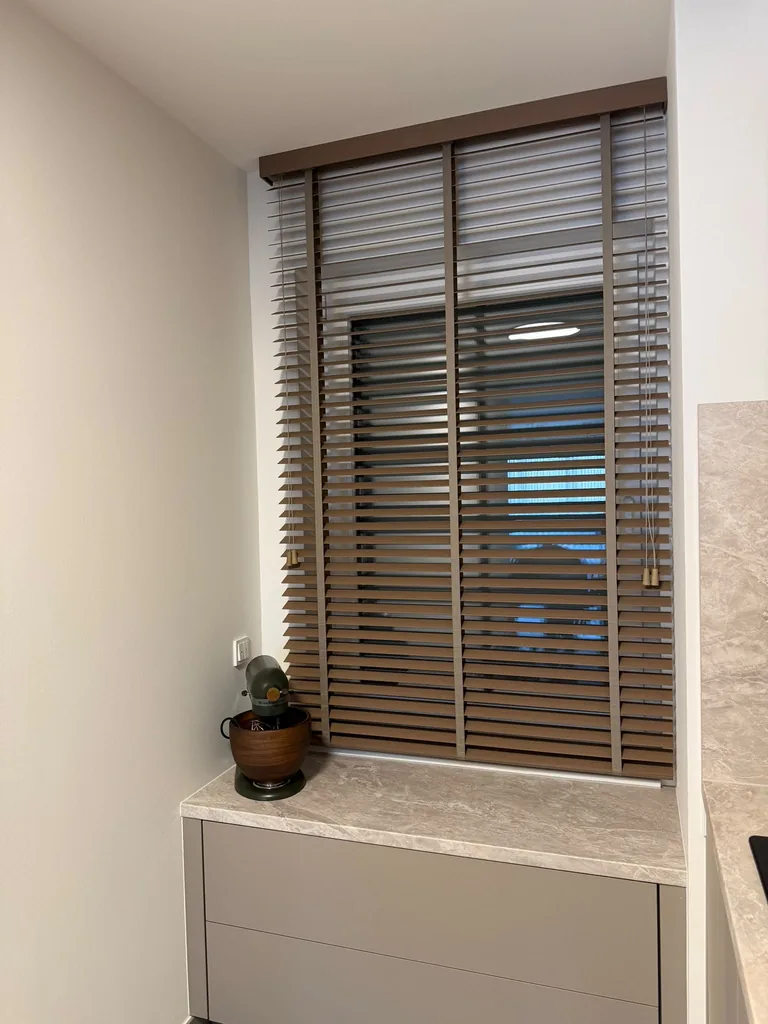 Braune Jalousie am Küchenfenster mit geöffneten Lamellen