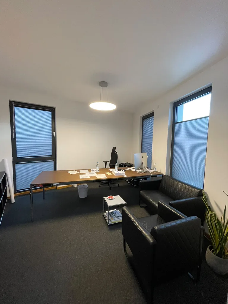 Graue Plissees an hohen Bürofenstern, teilweise als Sichtschutz nach oben gezogen