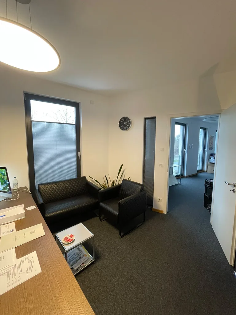 Graue Plissees an den Fenstern neben einer schwarzen Sitzgruppe im Büro